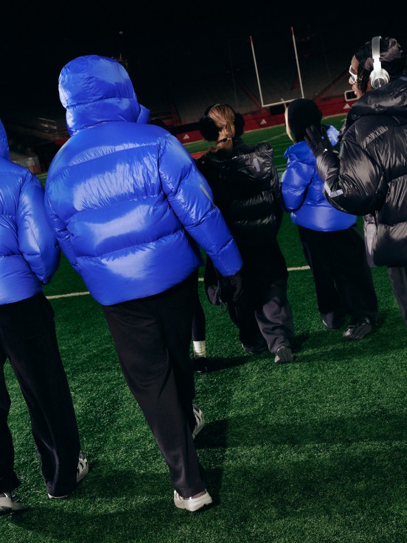 鮮やかなブルーのダウンジャケットを着た人びとが野原に集まり、背後には膨らませることができる大きな構造物が見えている。