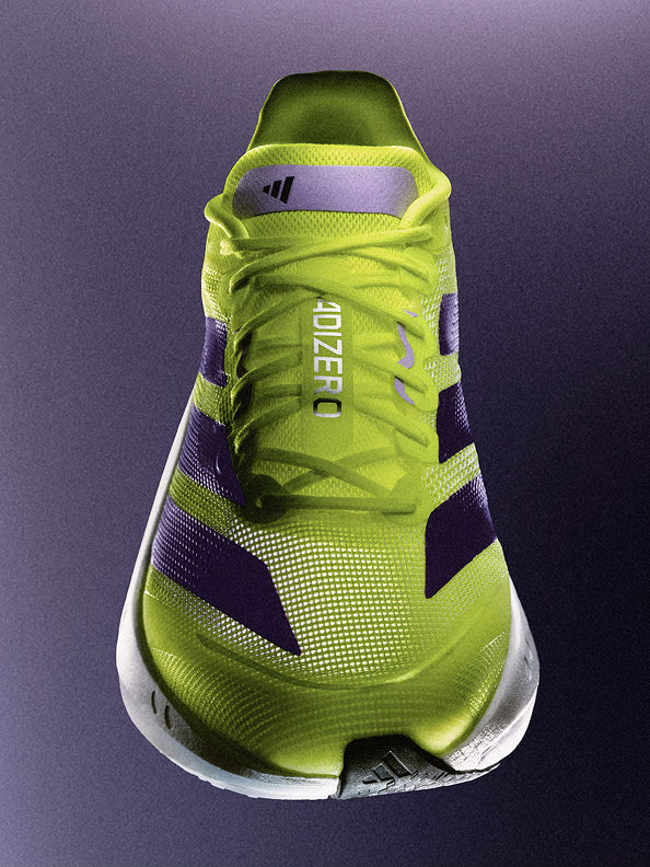 A vibrant green and black athletic shoe with a distinctive design and pattern stands out against a dark purple background.