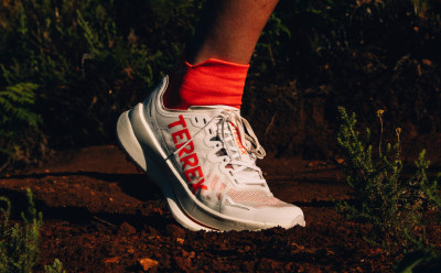 Close up of athlete’s foot wearing adidas Agravic trail running shoe while running outdoors. 