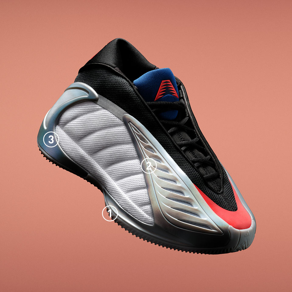 The grey, black and red adidas Anthony Edwards 2 basketball sneaker shown angled against a orange background. The shoe has three numbered callouts highlighting design features on the outsole, side panel, and heel.