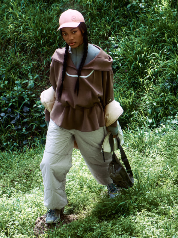 Eine Person, die einen braunen Mantel und eine braune Mütze trägt, läuft durch ein üppiges, grünes Feld.