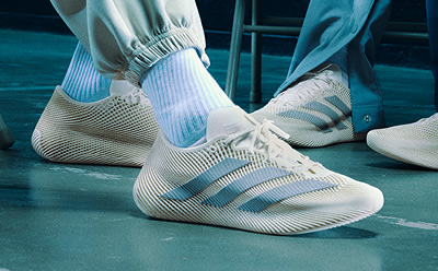The image shows a pair of white and blue sneakers with a distinctive striped pattern, set against a teal-colored background.