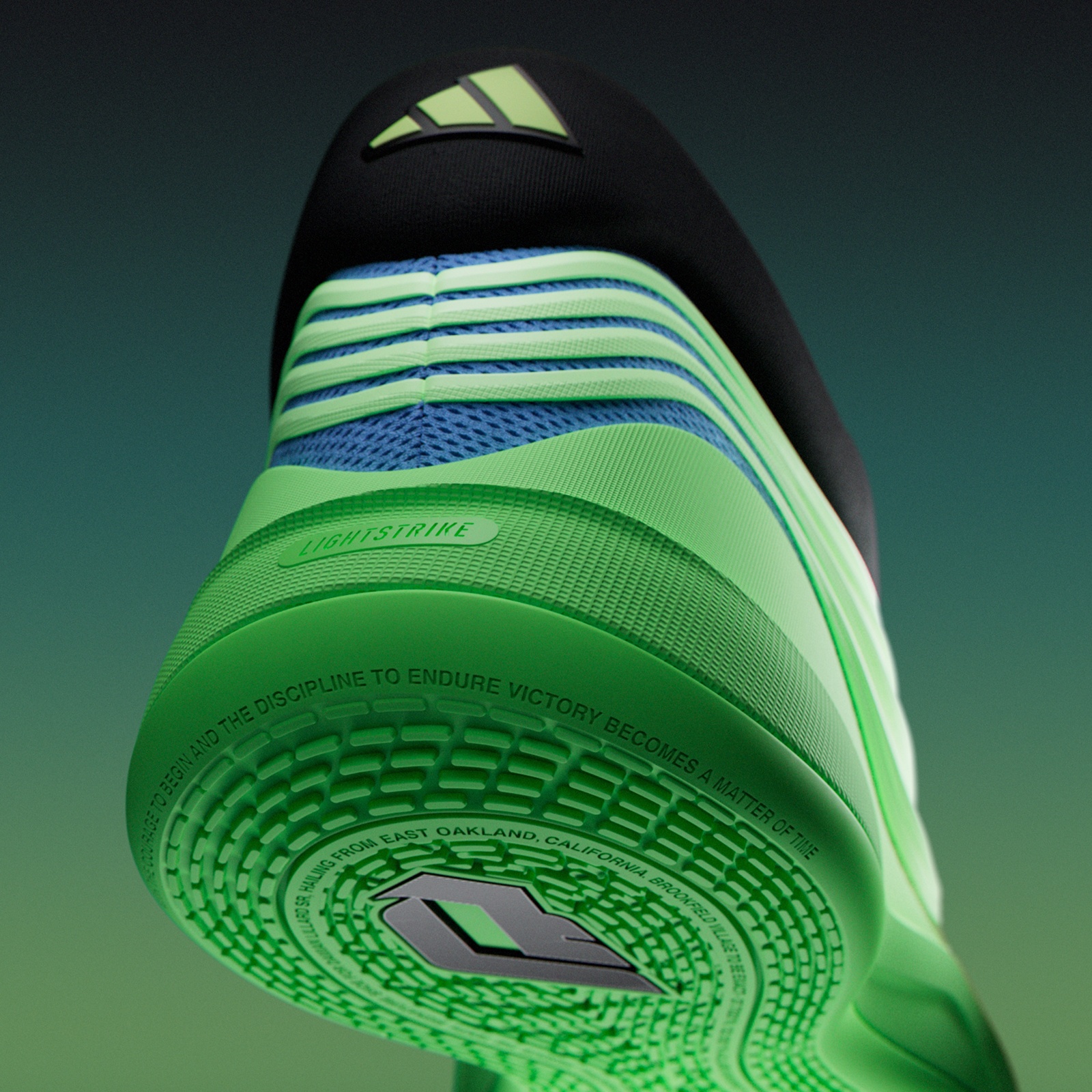 A close-up view of a green and blue athletic shoe with a black and white logo on the side, set against a dark green background.