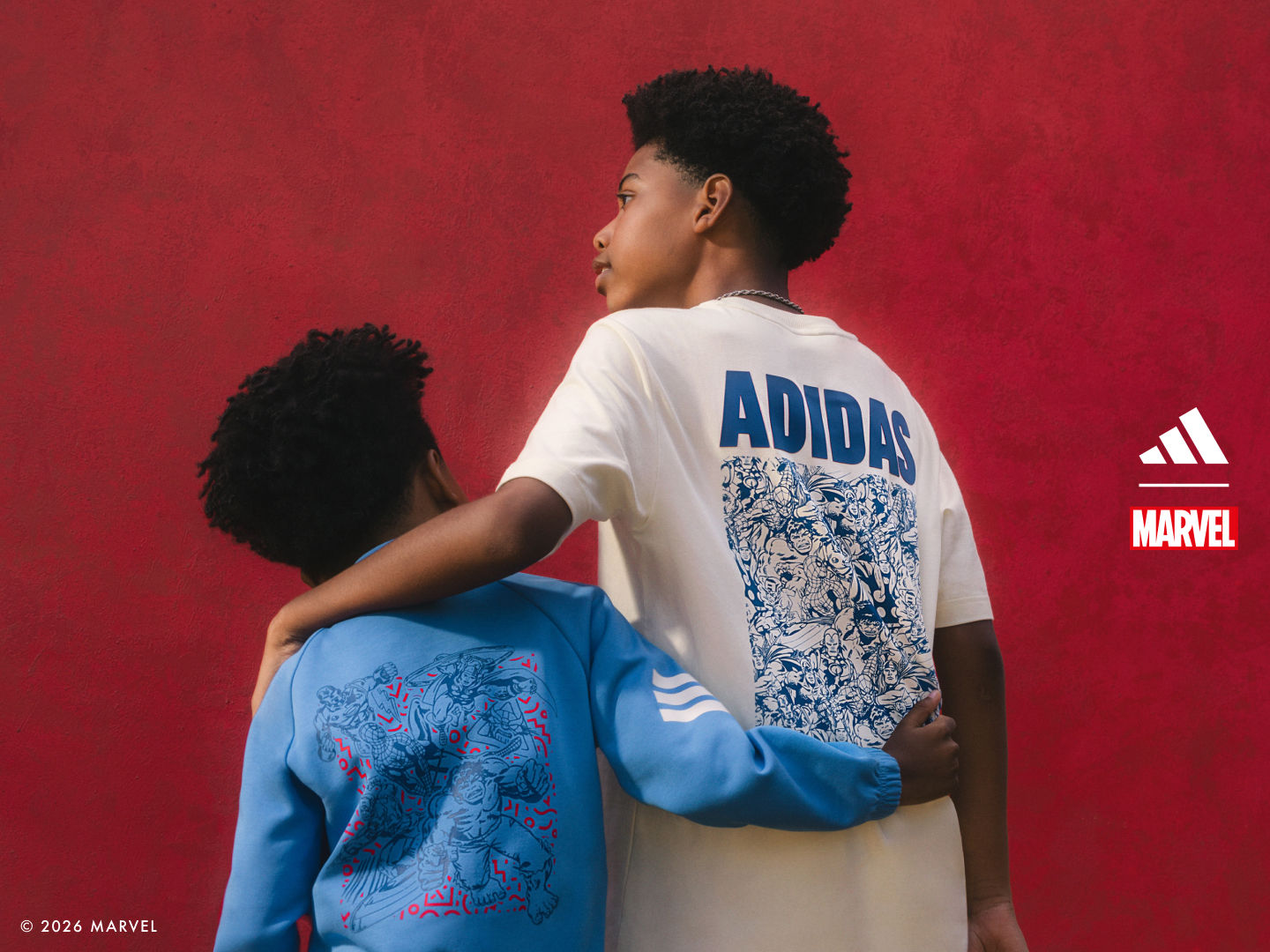 Elinde mavi bir sırt çantası ile adidas tişört giyen genç bir kişi, canlı kırmızı zemin üzerinde duruyor.