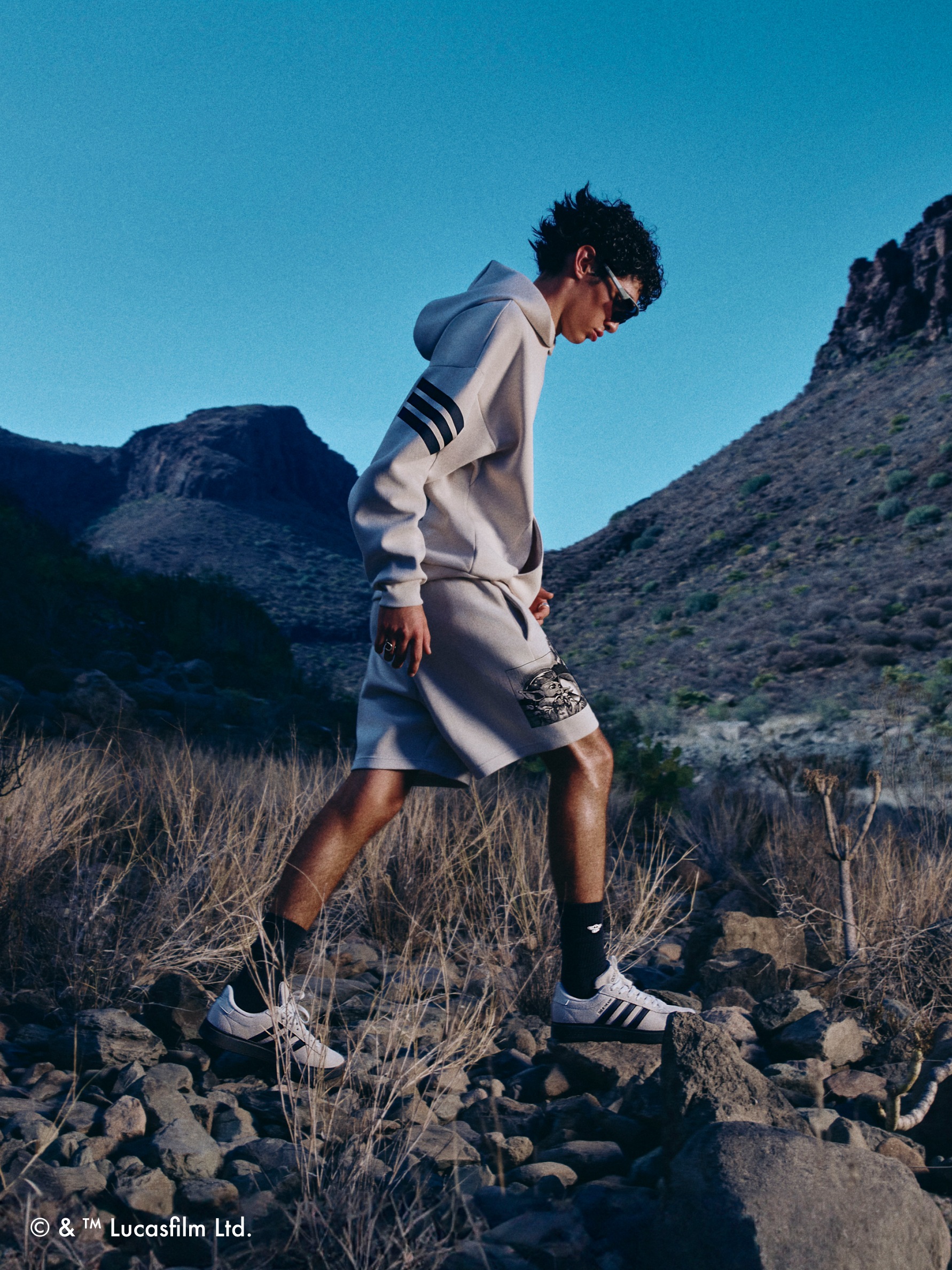 One adult walking across the desert wearing the adidas | Star Wars: The Mandalorian™ collection
