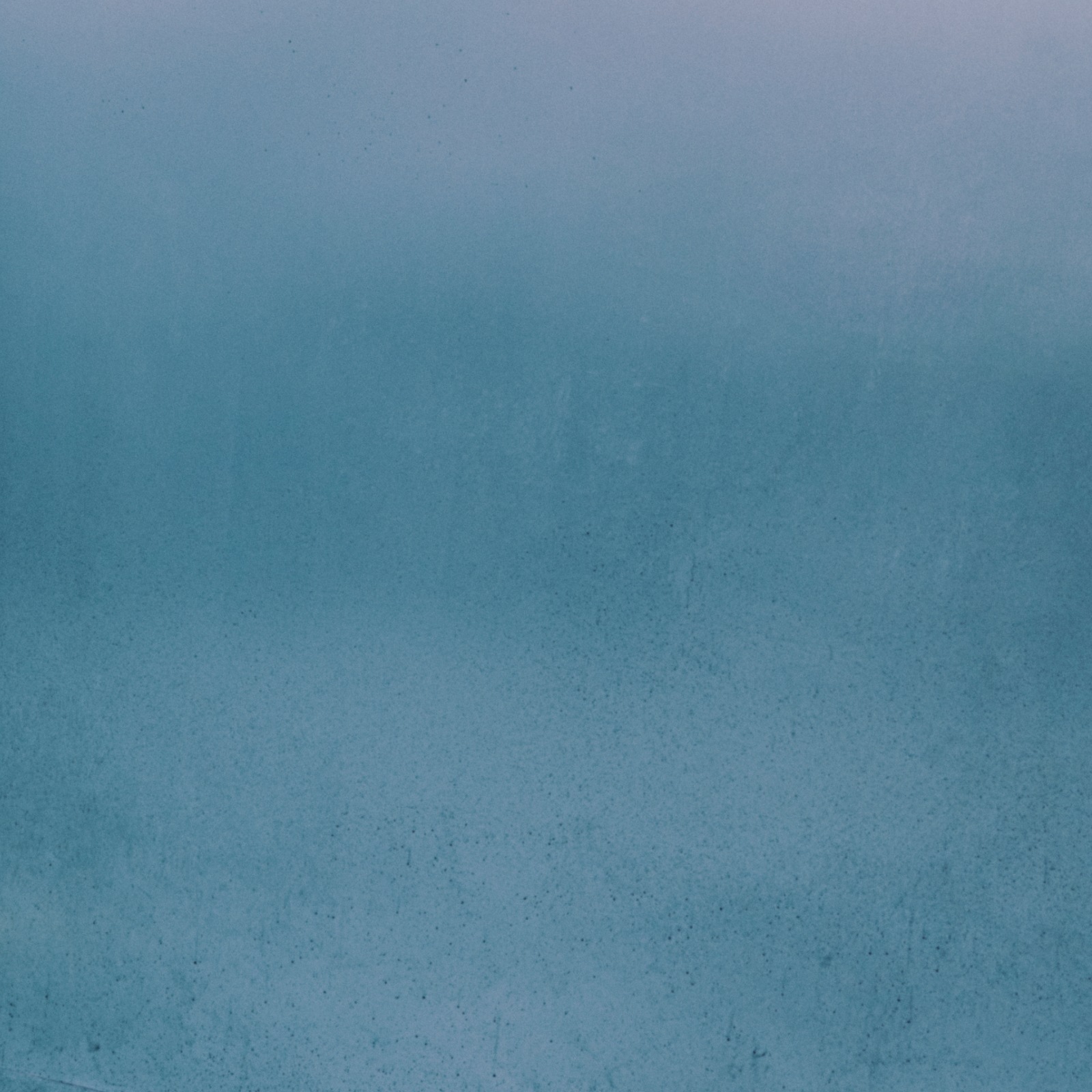 A serene, misty blue-green background with a subtle, hazy texture fills the frame.