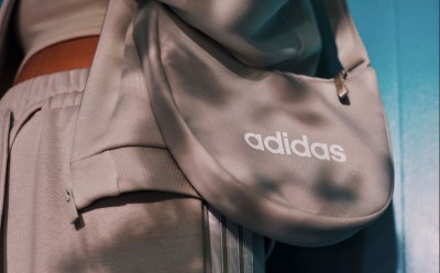 Een roze adidas rugzak met het logo van het merk prominent aanwezig tegen een wazige achtergrond.