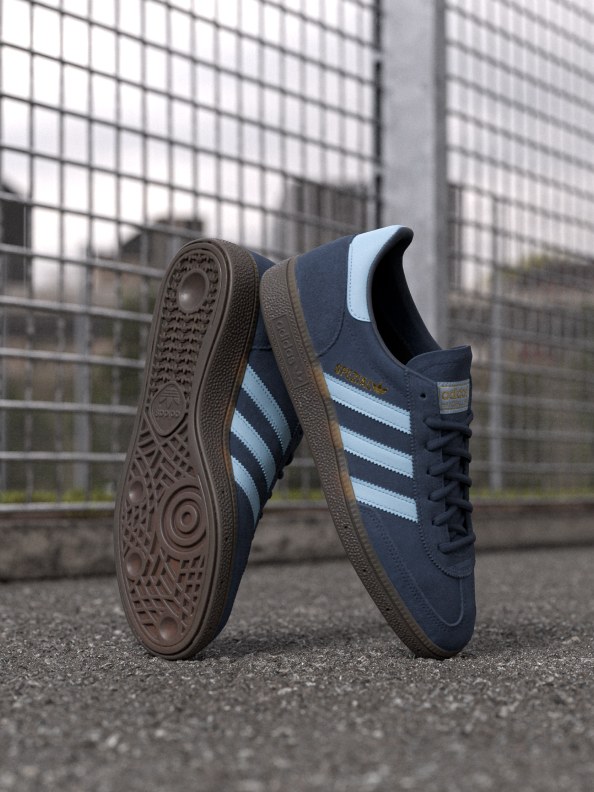 A pair of white and black adidas Spezial shoes on a concrete street. 
