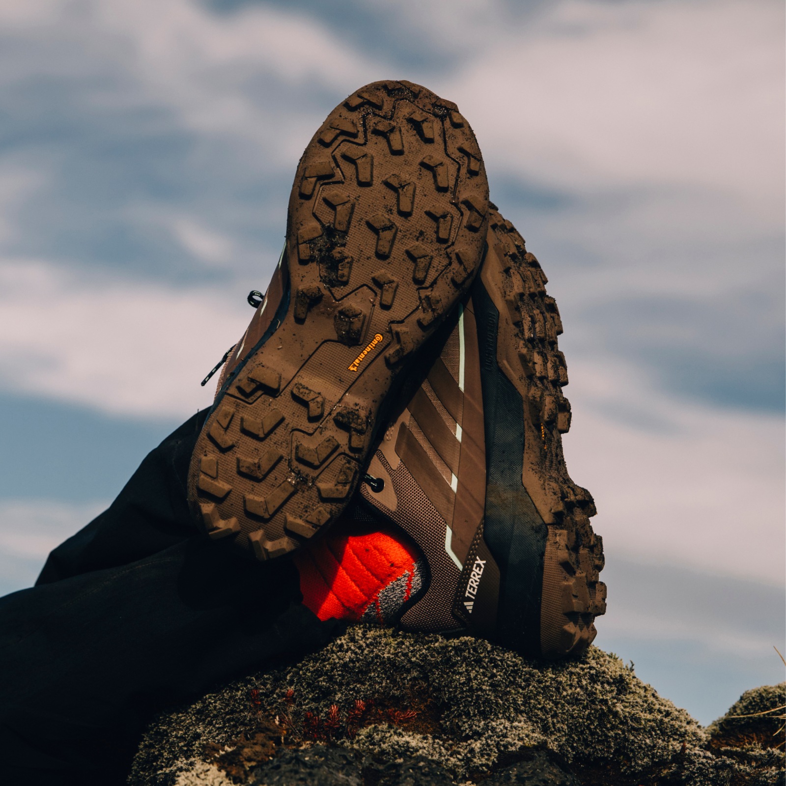 Brown Skychaser AX5 GTX shoes with crossed legs resting on a rock; Continental outsole shown.