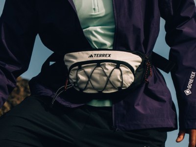 Η εικόνα δείχνει ένα άτομο που φοράει ένα μαύρο jacket και ένα τσαντάκι μέσης με λογότυπο Terrex, με ένα θολό φόντο.