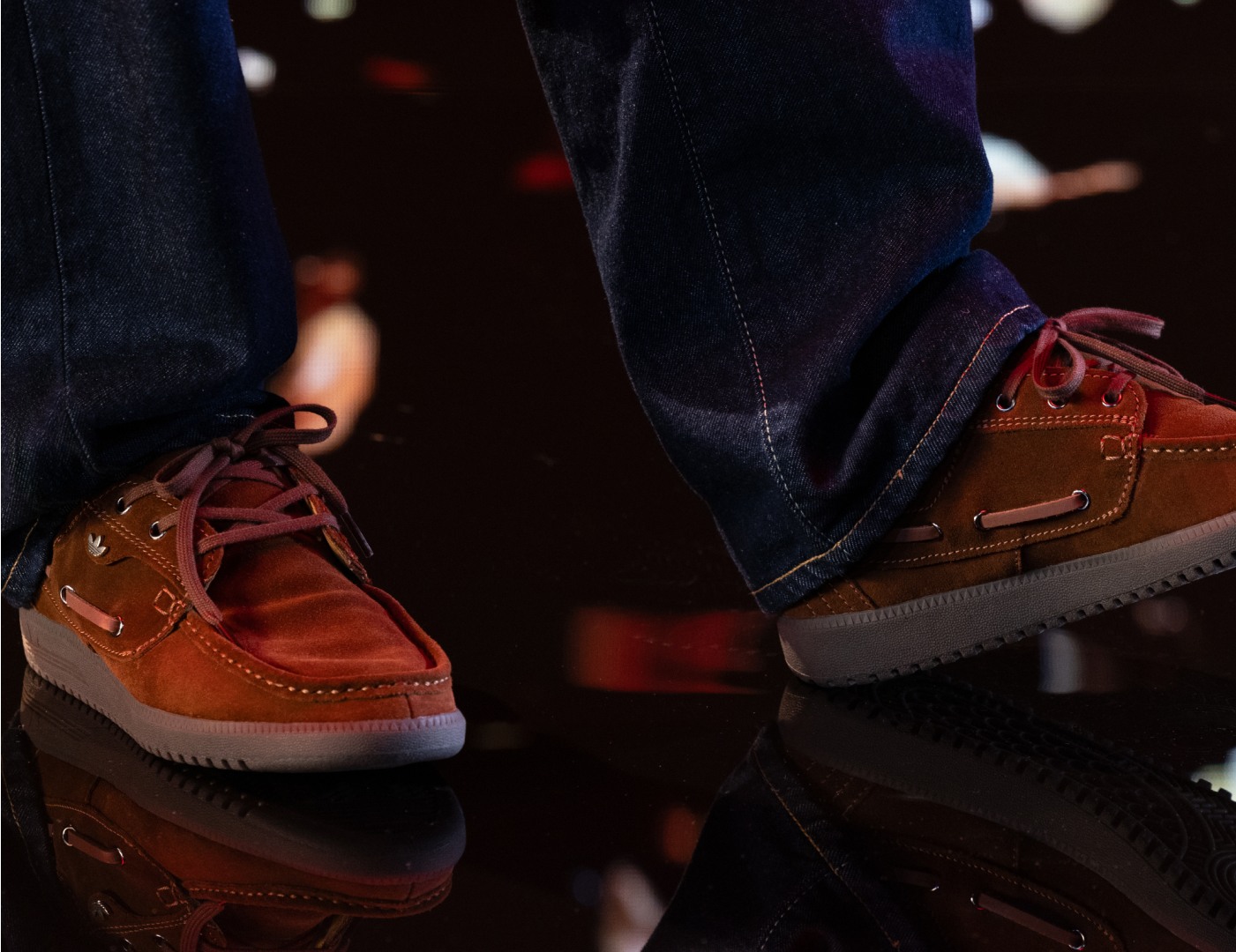 写真は、茶色のシューレース付きレザーシューズのペアで、リフレクターの表面に立っている人が履いているものです。