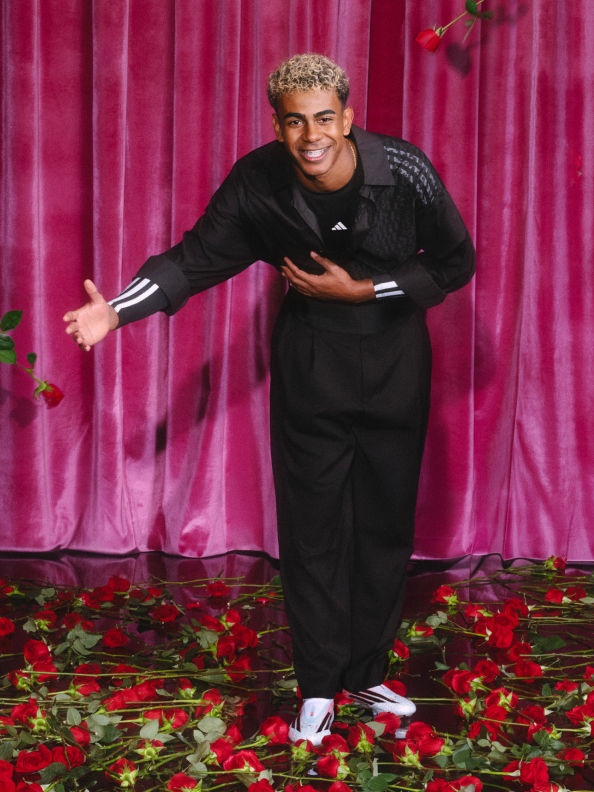 Lamine Yamal bows on a rose-covered stage, fully dressed in his adidas collection with a proud smile.