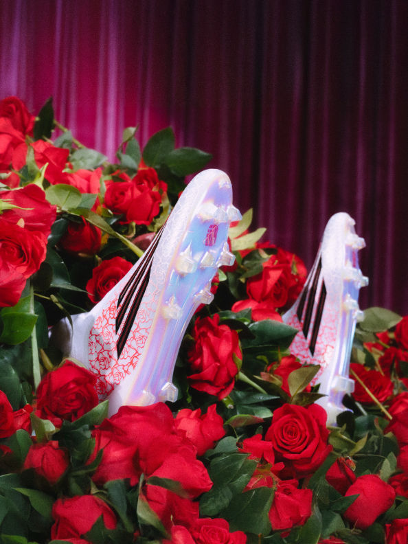 A crisp pair of F50 boots from the Lamine Yamal adidas collection, surrounded by roses and a pink curtain.