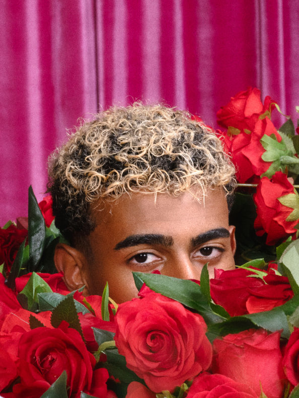 Lamine Yamal surrounded by roses and a pink curtain in the background.