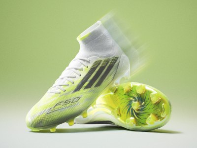 A white and neon green soccer cleat with a swirling pattern on the side, set against a vibrant green background.