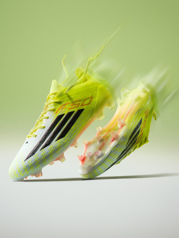 The image depicts a pair of vibrant, neon-colored athletic shoes in motion, with a blurred, green background suggesting a dynamic, energetic scene.