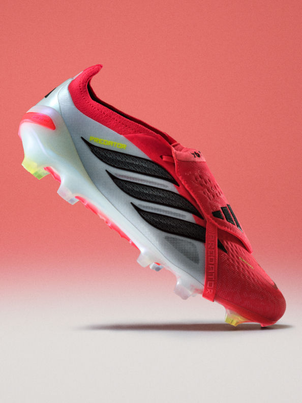 A vibrant red and white soccer cleat with black stripes and a yellow accent, set against a solid coral-colored background.