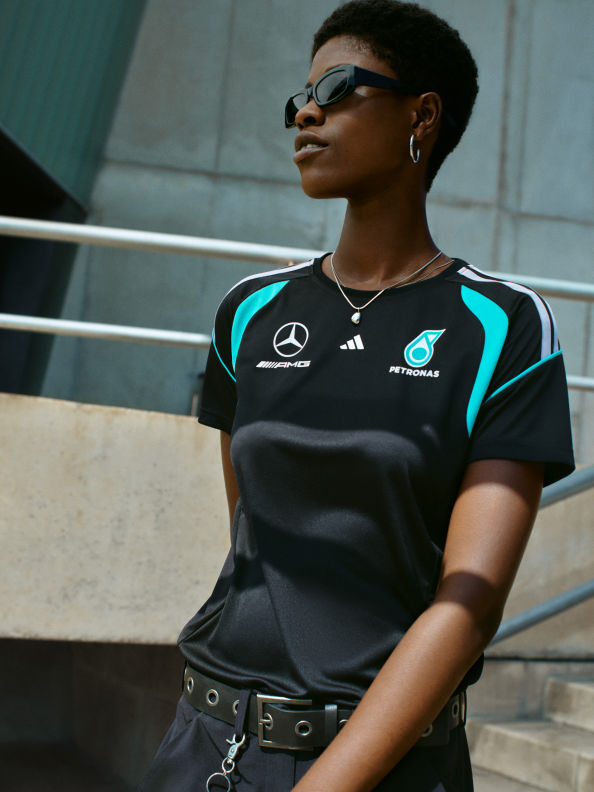 Một người mặc áo đấu thể thao màu đen và xanh đứng trước bức tường thuỷ tinh, với biểu hiện nghiêm túc trên mặt.