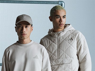 Dwóch młodych mężczyzn w swobodnych ubraniach sportowych, stojących przed białą ścianą.