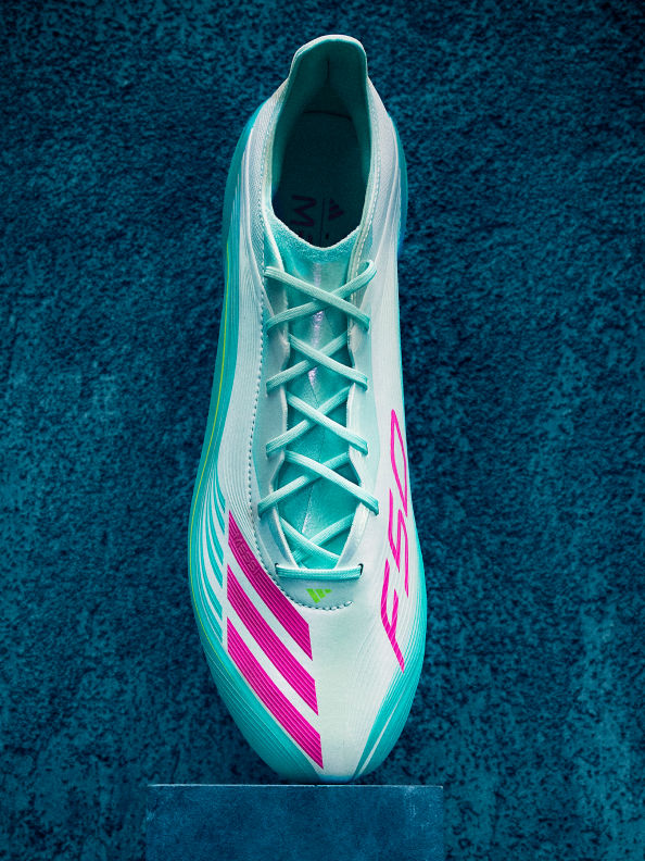 Đôi giày adidas Messi Samba màu xanh và đỏ đặt gọn gàng trên nền bê tông.