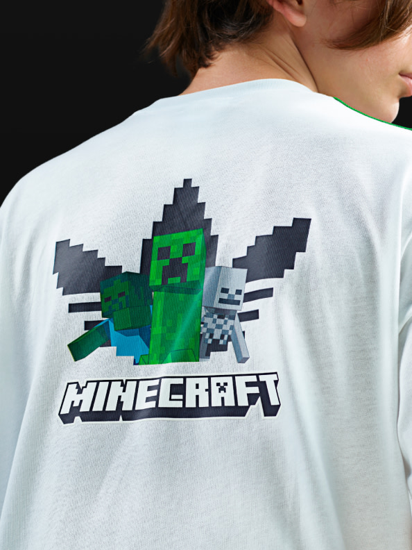 The image depicts a white t-shirt with a Minecraft-themed graphic on the back, featuring pixelated characters and the Minecraft logo.