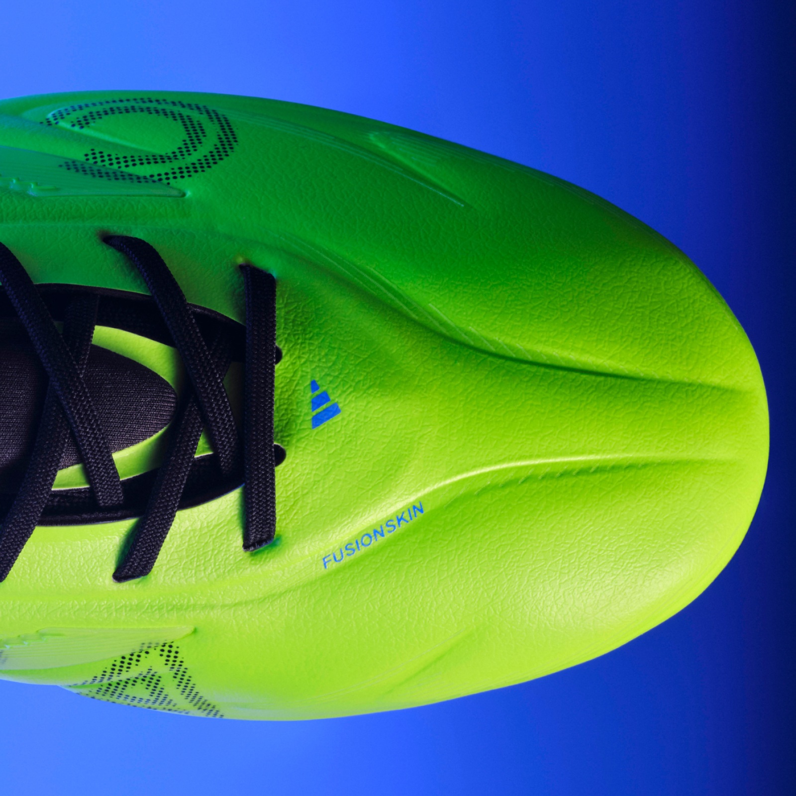 A vibrant green soccer cleat against a bright blue sky, showcasing the intricate design and texture of the shoe.