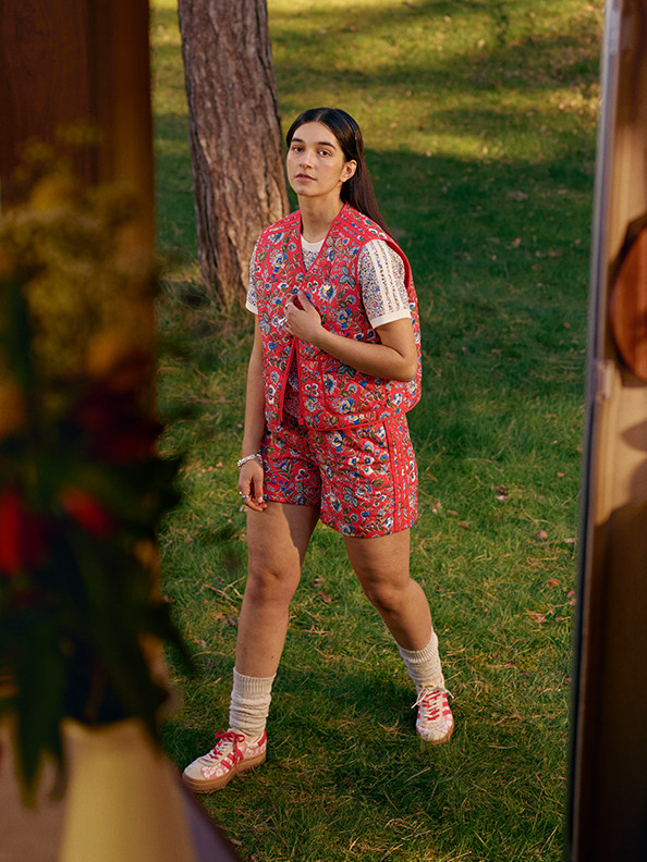a girl outdoors wears shorts and a pink floral vest.