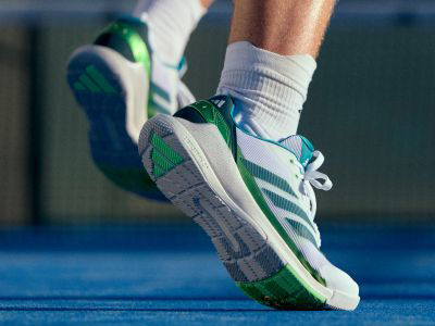 The image shows a pair of athletic shoes with a white, green, and blue color scheme.