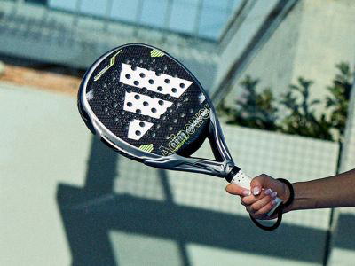 A person's hand holding a black and white padel racket
