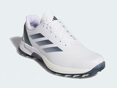 Un paio di scarpe da golf adidas bianche e grigie con le inconfondibili 3 strisce del brand sul lato, su uno sfondo chiaro.