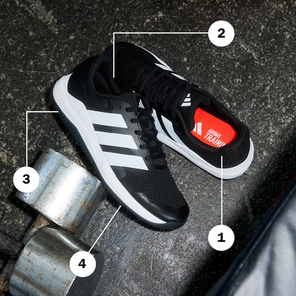 Černobílé sportovní boty s červenými detaily na tmavém, texturovaném povrchu obklopeném kovovými předměty.