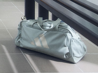 A grey sports bag with white stripes sits on a tiled floor, with a wooden staircase visible in the background.