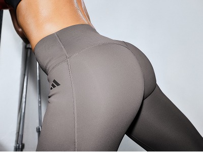 The image shows a close-up view of a person's lower body wearing grey athletic leggings, with a plain background.