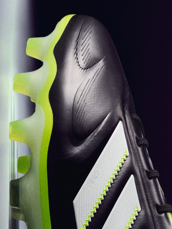 A close-up view of a black and white abstract sculpture with sharp, angular shapes and a vibrant yellow accent against a dark background.