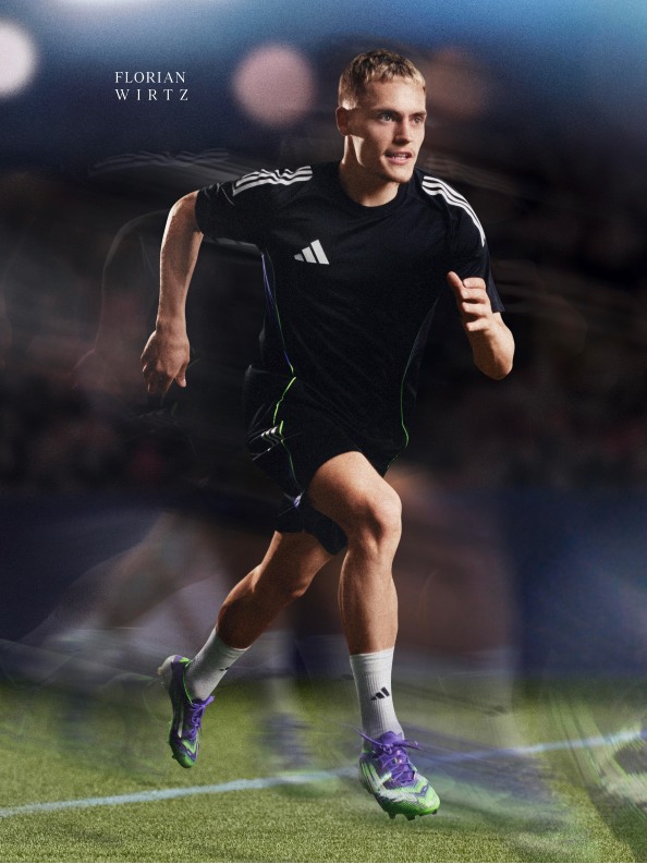 Ein junger Mann in schwarzer Sportkleidung läuft auf einem Grasfeld mit verschwommenem Hintergrund.