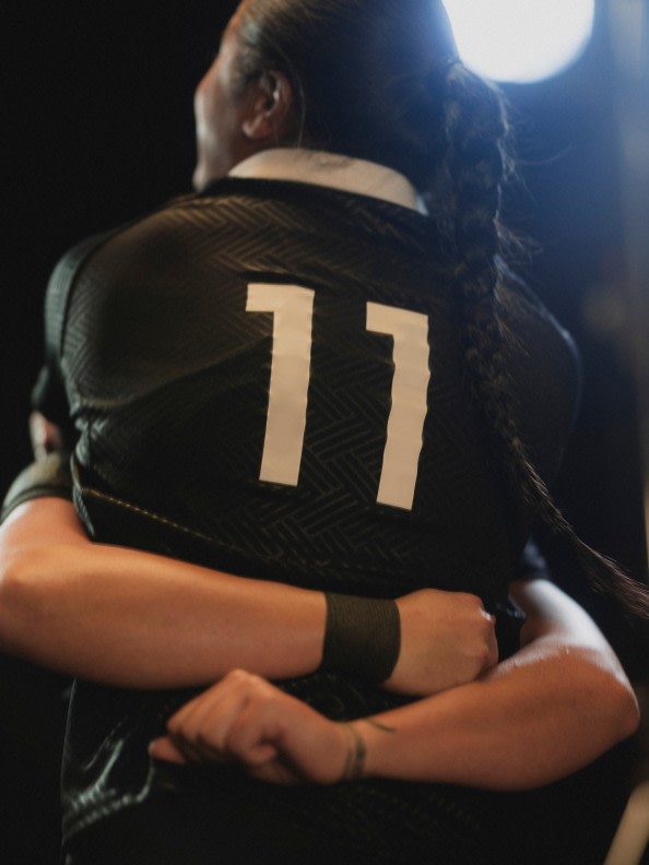 A person wearing a black jersey with the number "11" on the back, standing in a dimly lit environment.