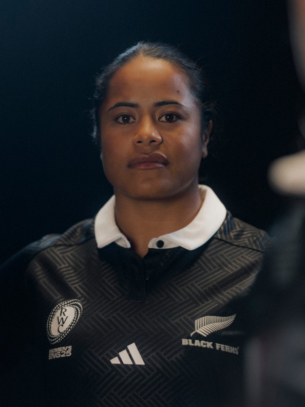 The image shows a person wearing a black and white sports jersey with the text "Black Ferns" on it, standing against a dark background.