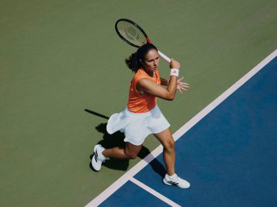 Image de Daria Kasatkina portant la nouvelle chaussure adidas Barricade en blanc, prête à frapper le ballon sur le court de tennis.