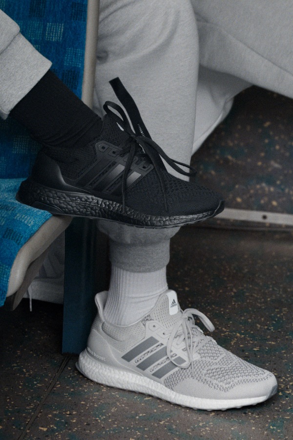 A pair of black sneakers and white athletic shoes are visible on a tiled floor, with a blue and white patterned background.