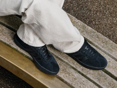 The image shows a pair of black leather shoes on a granite surface, with a white pant leg visible above them.