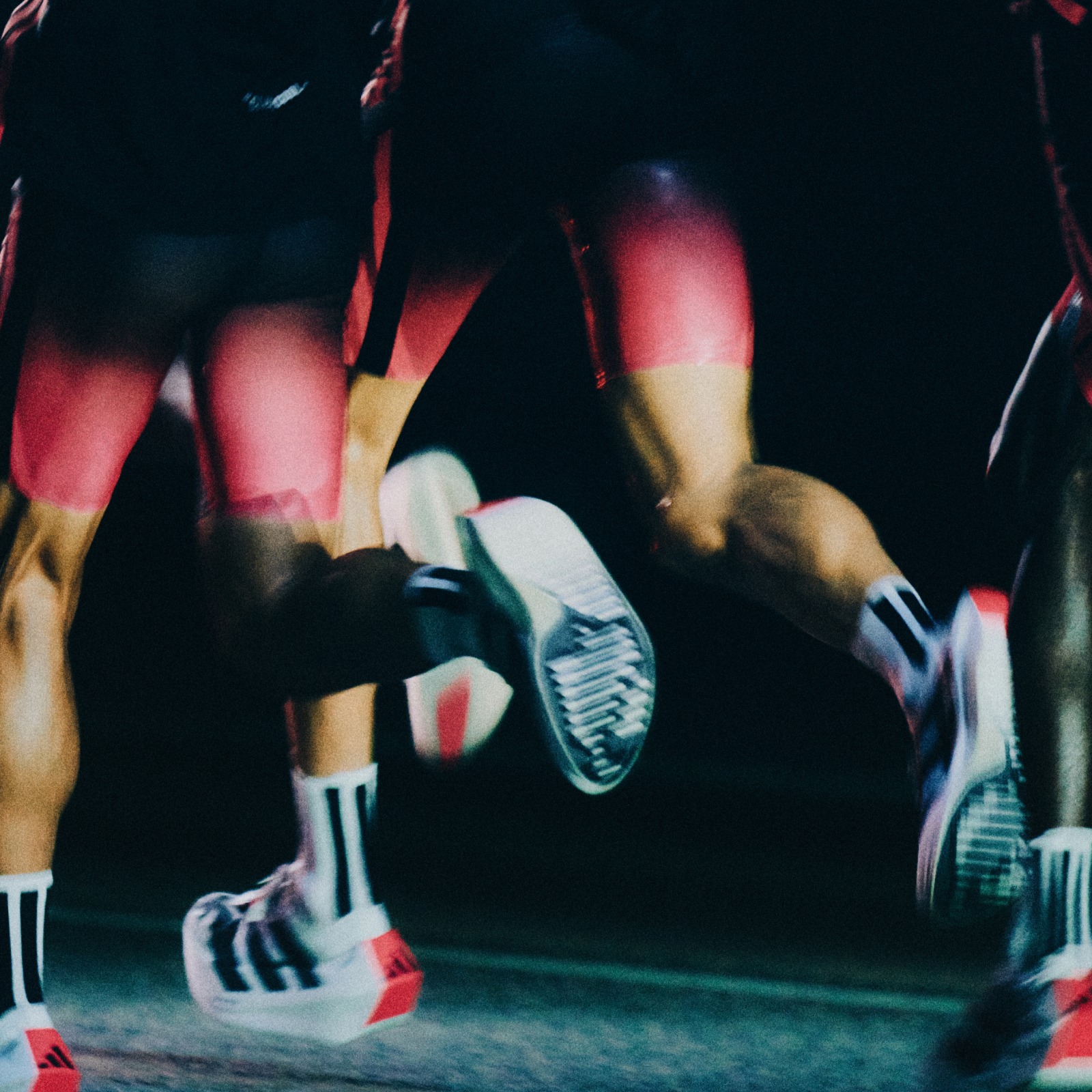 The image depicts a person's lower body and feet in motion, with colorful athletic shoes and a dark background, suggesting an athletic or sports-related activity.