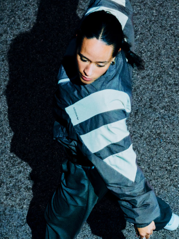 A person wearing a striped jacket and hat is crouched down on a dark, textured surface.