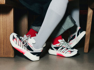 The image shows a pair of colorful athletic shoes with red, white, and black accents, resting on a wooden surface.