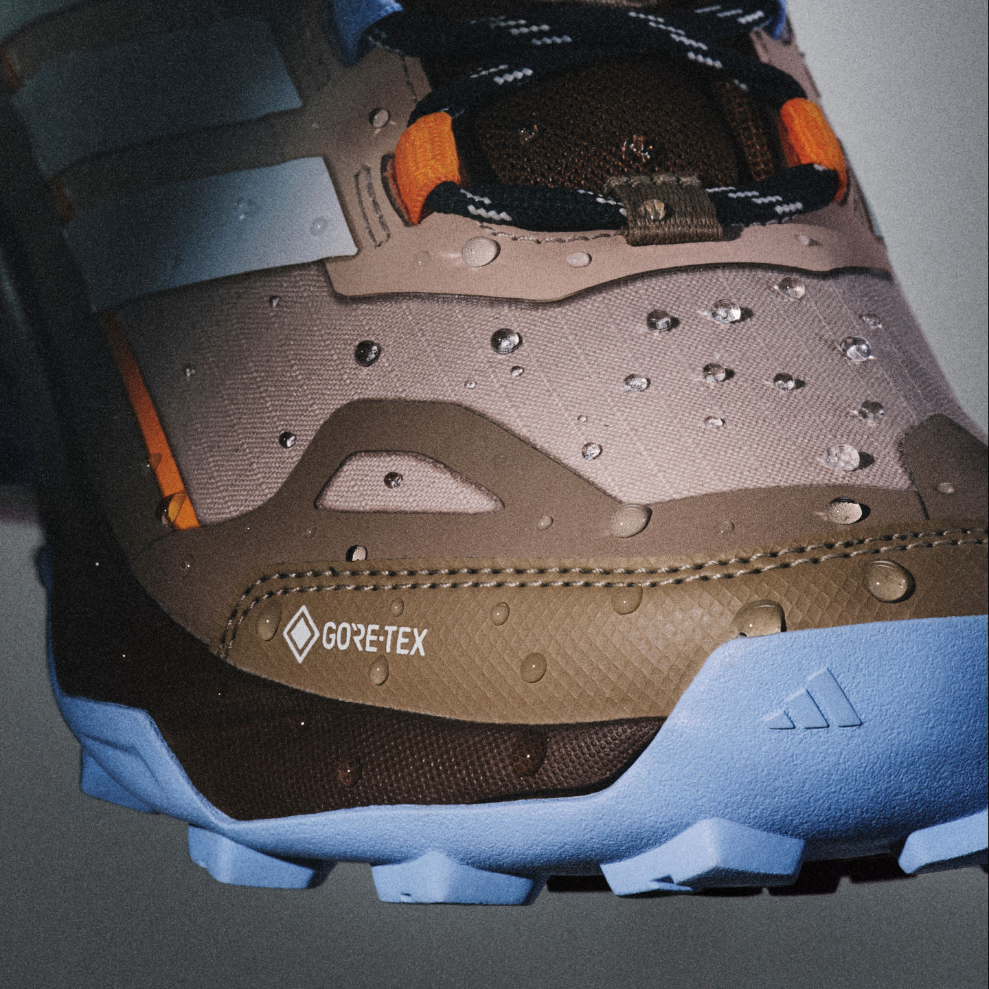 La imagen muestra un primer plano de una bota de montaña con una etiqueta de Gore-Tex, una suela texturizada resistente al desgaste y un material resistente al agua en el empeine.