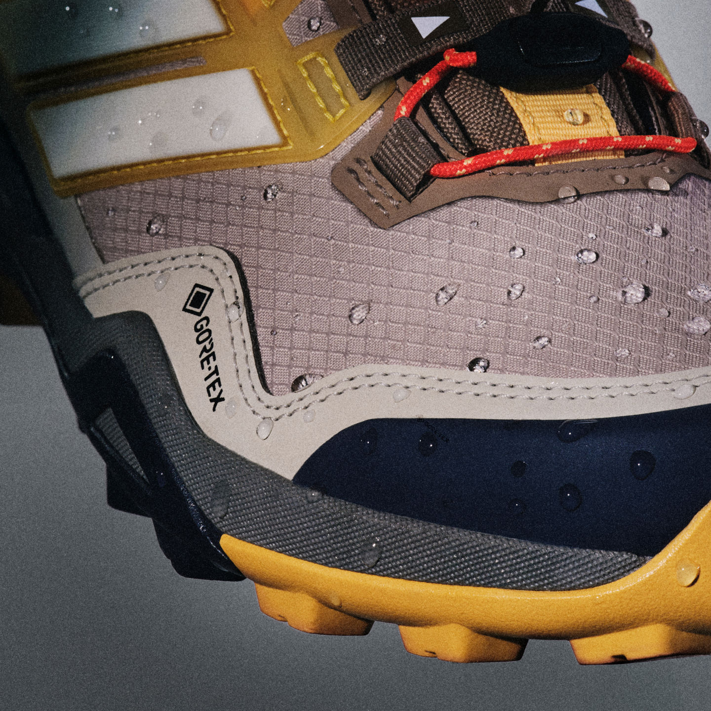 Na zdjęciu widać z bliska parę mocnych, outdoorowych butów hikingowych z teksturowaną, wodoodporną cholewką i grubą, żółtą podeszwą. Buty wydają się być dobrze noszone i zaprojektowane z myślą o przyczepności i trwałości w trudnym terenie.
