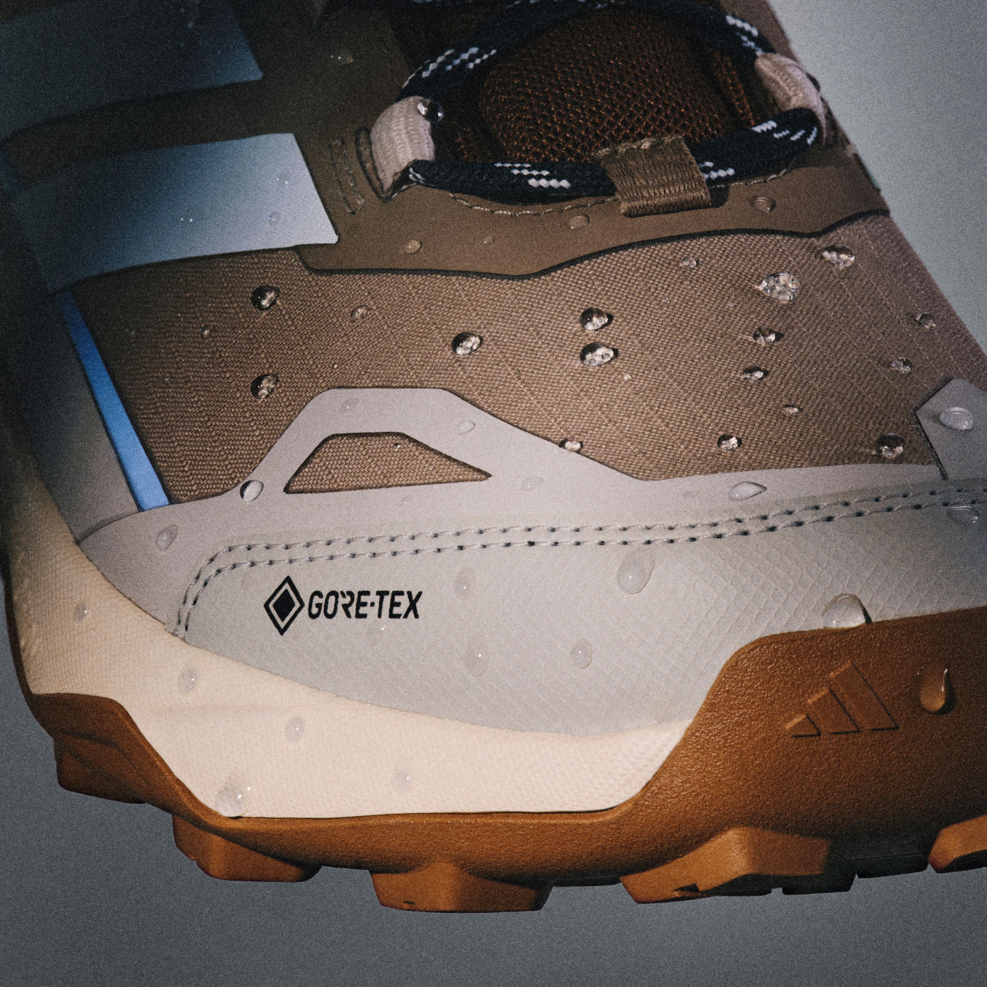 Nahaufnahme eines robusten Wanderschuhs in Beige mit Gore-Tex Label, strukturierter Sohle und dunklem Obermaterial.