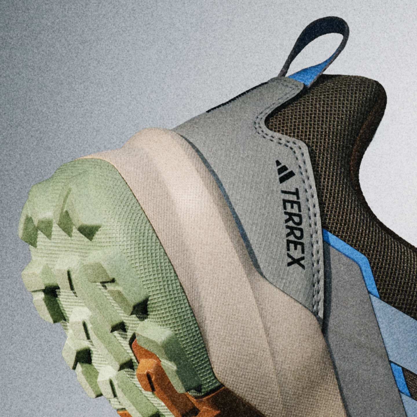 Nahaufnahme eines grau-blauen Sportschuhs mit strukturierter Sohle und auffälligem adidas Logo an der Seite.