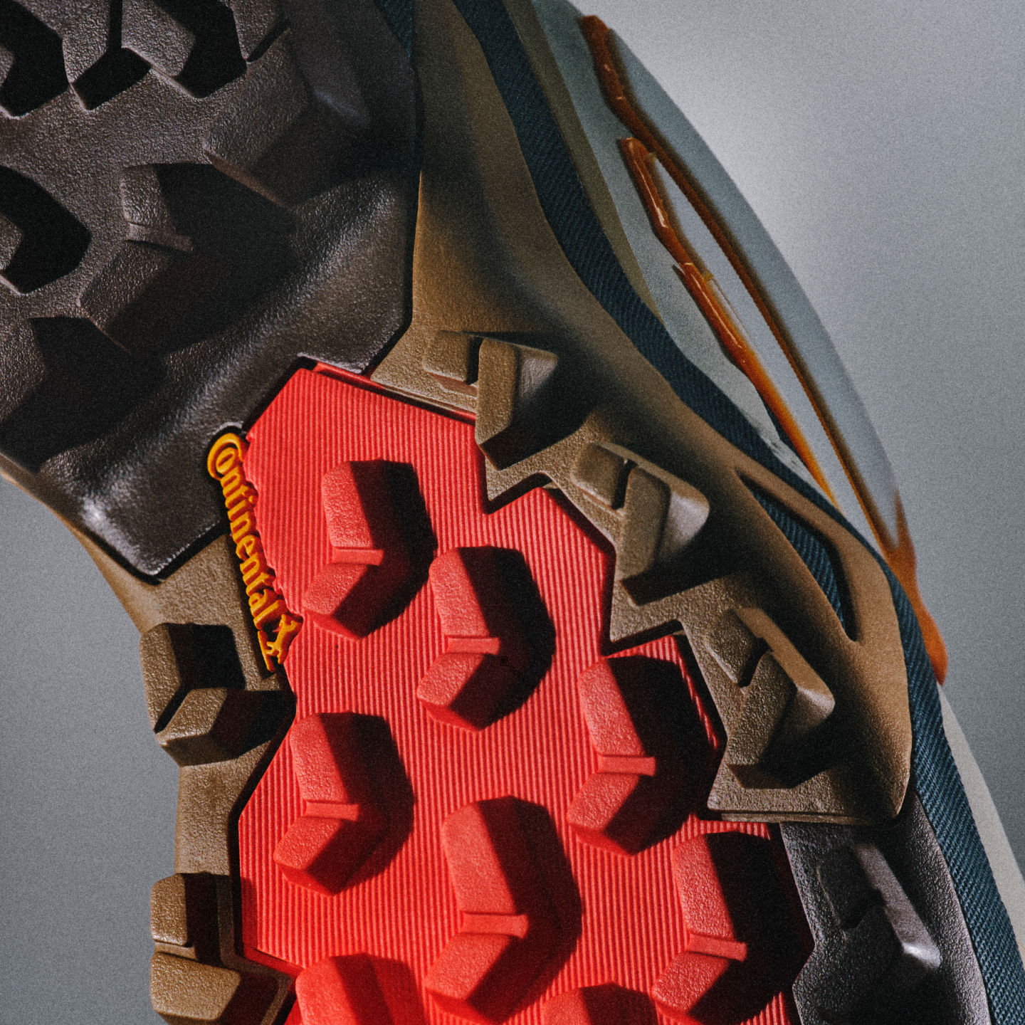 Na zdjęciu widać z bliska mocną, teksturowaną podeszwę z wyróżniającym się, czerwonym logo lub elementem designu na środku.