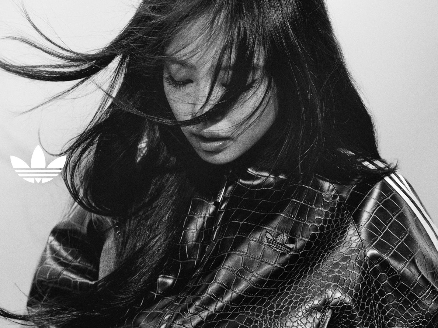 ภาพพอร์เทรทขาวดำจับการเคลื่อนไหวกลางคน JENNIE ขณะสวมเสื้อแจ็คเก็ตพิมพ์ลายแบบจระเข้ มีผิวสัมผัสบางเบาที่สื่อถึงการเคลื่อนไหวและทัศนคติอย่างแท้จริง