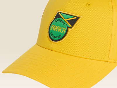 A yellow baseball cap with a green and yellow emblem featuring the text "JAMAICA" and the Jamaican flag.